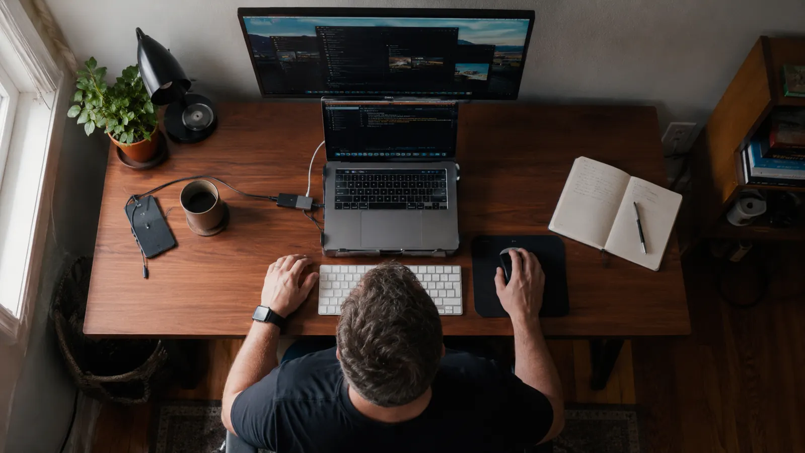 Overhead view of a 48 by 24 inch desktop showing a laptop, monitor, and notebook fitted closely together with little spare room