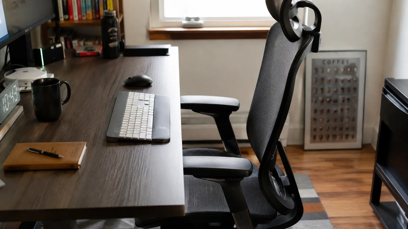 SIHOO B100 chair rolled up to a laminate desk in a tight corner home office, armrests catching the desk lip