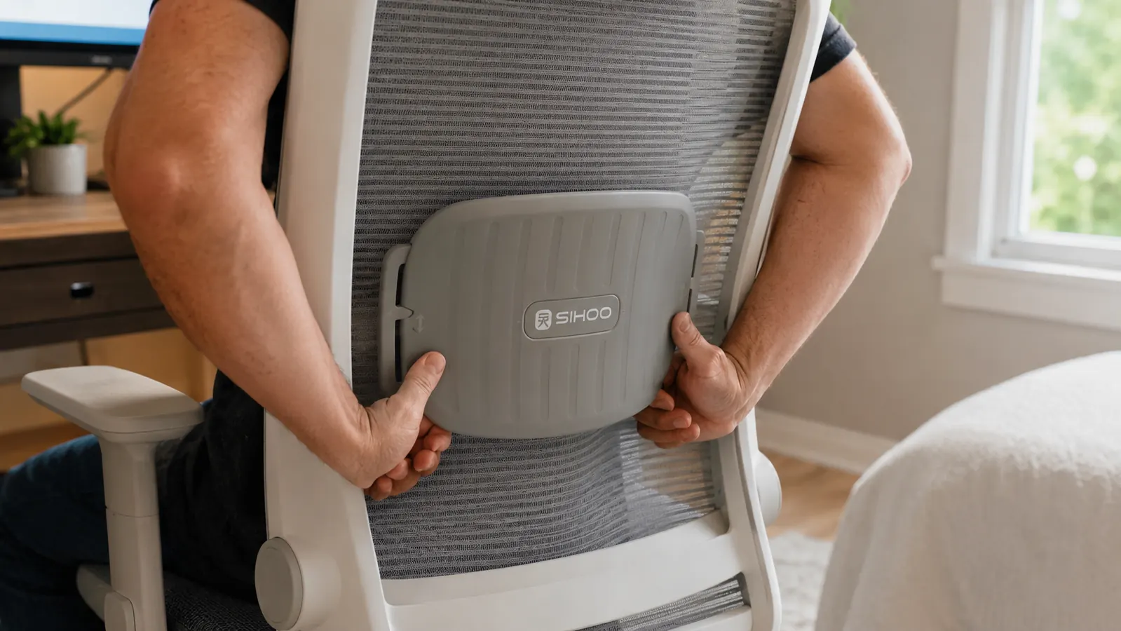Hand adjusting the lumbar support pad on the back of the SIHOO B100 mesh office chair